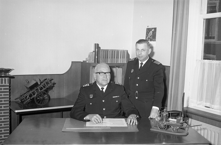 850317 Portret van scheidend brandweercommandant J. Das (zittend), met rechts zijn opvolger J. 't Lam, op zijn ...